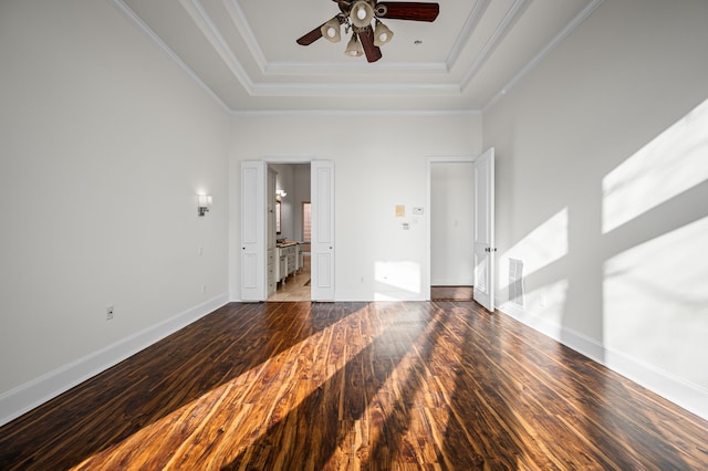 empty room with crown molding, ceiling fan, a tray ceiling, and dark hardwood / wood-style flooring