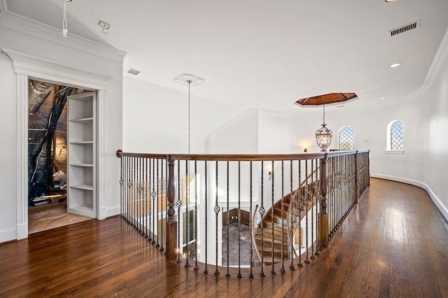 corridor with crown molding, hardwood / wood-style floors, and a notable chandelier