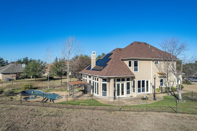 back of house featuring a yard, a sunroom, and solar panels