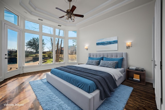 bedroom featuring crown molding, wood finished floors, visible vents, and a tray ceiling