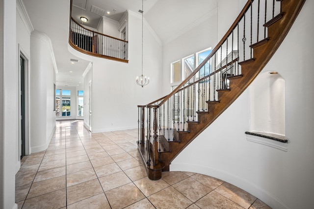 tiled entryway featuring an inviting chandelier, baseboards, a towering ceiling, and ornamental molding