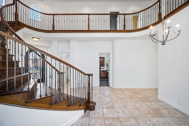 staircase with tile patterned floors, ornamental molding, a high ceiling, baseboards, and a chandelier