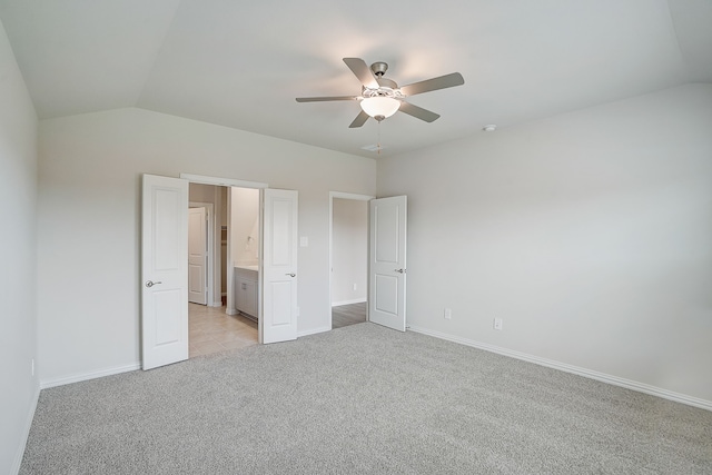 unfurnished bedroom featuring ceiling fan, light colored carpet, ensuite bath, and vaulted ceiling