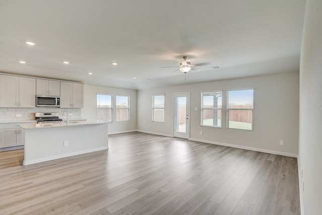 kitchen with white cabinets, tasteful backsplash, appliances with stainless steel finishes, and open floor plan