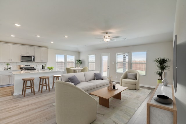 living room featuring ceiling fan, sink, and light hardwood / wood-style floors