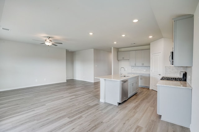 kitchen featuring ceiling fan, light hardwood / wood-style flooring, stainless steel dishwasher, an island with sink, and decorative backsplash