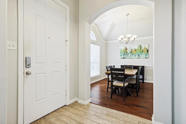 dining room featuring an inviting chandelier, hardwood / wood-style flooring, and vaulted ceiling