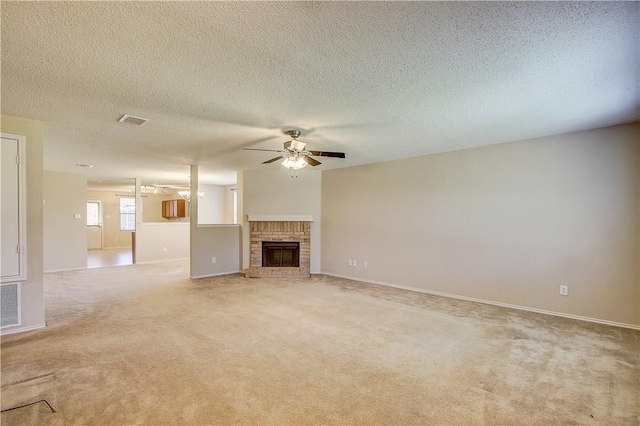 unfurnished living room with a textured ceiling, light colored carpet, a brick fireplace, and ceiling fan