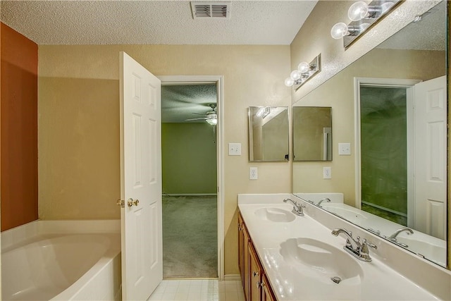 bathroom with a textured ceiling, vanity, ceiling fan, and a tub