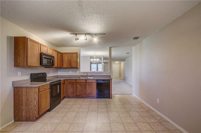 kitchen featuring sink, rail lighting, an inviting chandelier, a textured ceiling, and black appliances