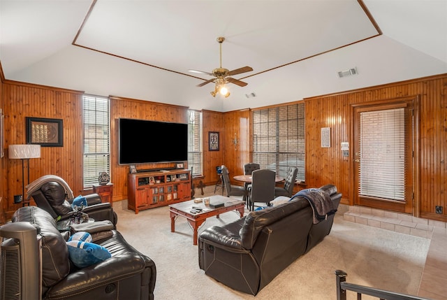 carpeted living room with vaulted ceiling, ceiling fan, and wooden walls