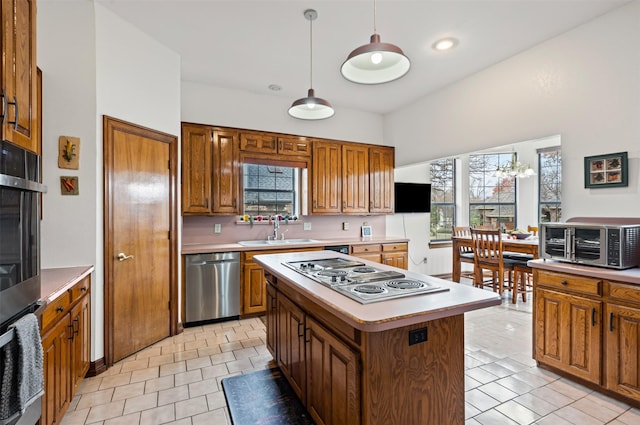 kitchen with dishwasher, sink, a kitchen island, pendant lighting, and a healthy amount of sunlight