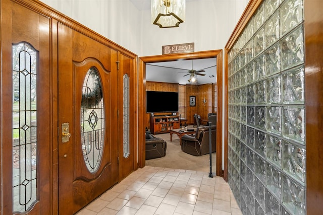 carpeted entryway featuring ceiling fan and wood walls