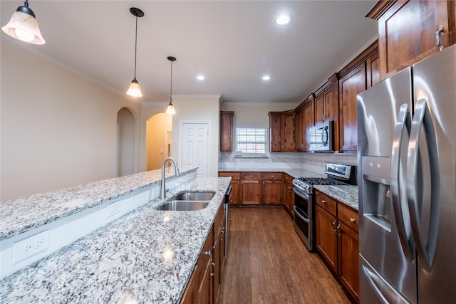 kitchen featuring light stone countertops, pendant lighting, stainless steel appliances, sink, and ornamental molding