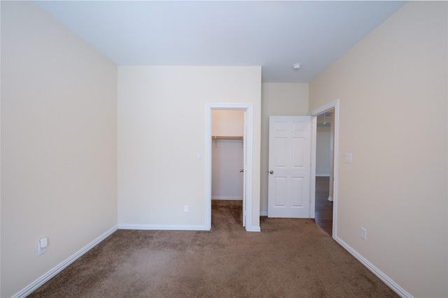 unfurnished bedroom featuring a walk in closet, a closet, and carpet flooring