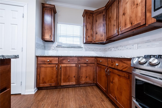 kitchen featuring decorative backsplash, light stone counters, stainless steel appliances, and ornamental molding