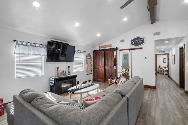 living room with wood-type flooring, a barn door, lofted ceiling with beams, and ceiling fan