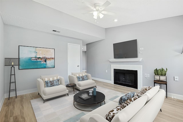 living room with a tiled fireplace, hardwood / wood-style floors, vaulted ceiling, and ceiling fan