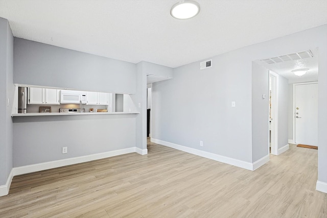 unfurnished living room with light hardwood / wood-style floors and a textured ceiling