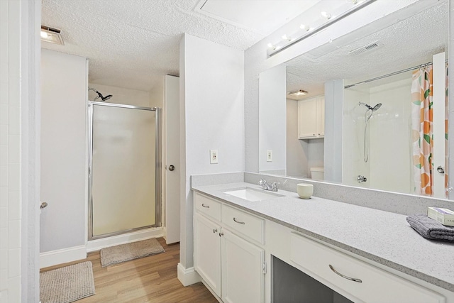 bathroom featuring walk in shower, vanity, a textured ceiling, hardwood / wood-style floors, and toilet