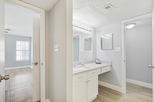 bathroom featuring hardwood / wood-style floors, vanity, a textured ceiling, and ceiling fan