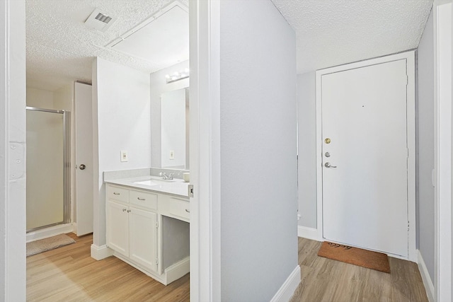 bathroom with hardwood / wood-style floors, vanity, a shower with door, and a textured ceiling