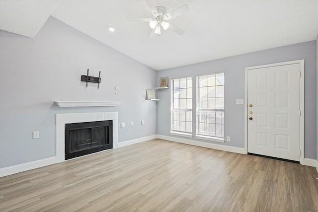 unfurnished living room with a fireplace, light hardwood / wood-style flooring, vaulted ceiling, and ceiling fan