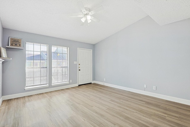 unfurnished room featuring a textured ceiling, light hardwood / wood-style flooring, ceiling fan, and vaulted ceiling