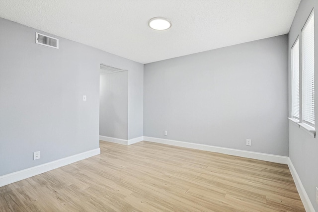 spare room featuring light hardwood / wood-style floors and a textured ceiling