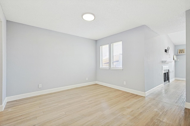 spare room with a textured ceiling and light hardwood / wood-style floors