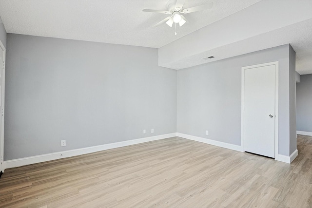 empty room with a textured ceiling, light wood-type flooring, and ceiling fan