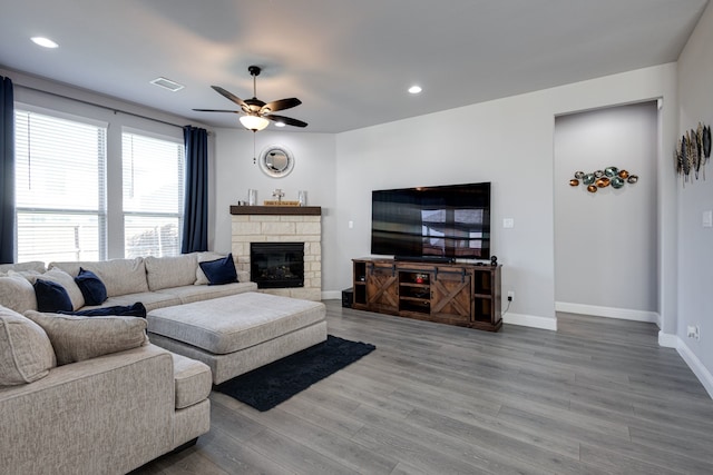 living room featuring wood-type flooring, ceiling fan, and a fireplace