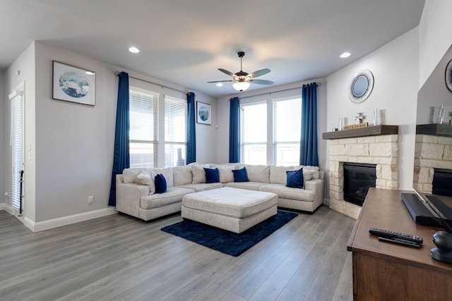 living room featuring ceiling fan, a healthy amount of sunlight, a fireplace, and light hardwood / wood-style floors