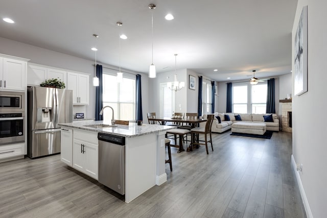 kitchen featuring white cabinetry, stainless steel appliances, sink, and an island with sink