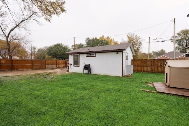 back of house with a storage shed and a lawn