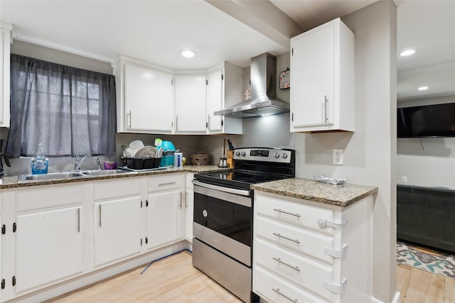 kitchen with wall chimney exhaust hood, sink, white cabinets, light hardwood / wood-style floors, and stainless steel electric range