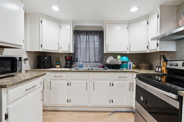 kitchen featuring wall chimney range hood, sink, appliances with stainless steel finishes, light stone counters, and white cabinetry