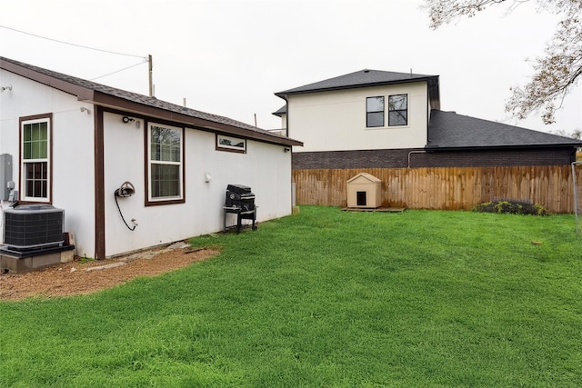 back of property with central AC and a yard