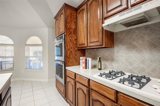 kitchen with double oven, white gas cooktop, tasteful backsplash, and light tile patterned floors