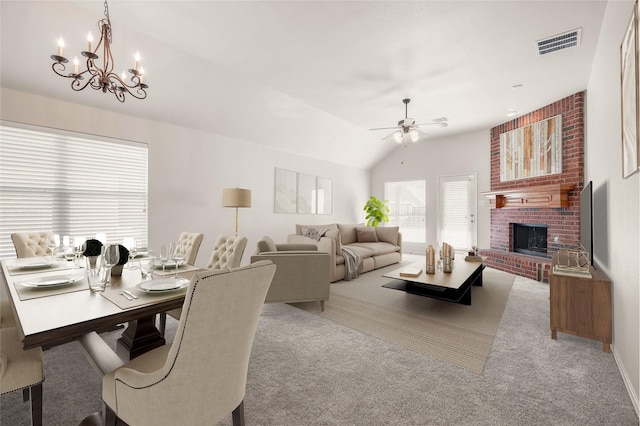 carpeted dining space with vaulted ceiling, ceiling fan with notable chandelier, and a brick fireplace