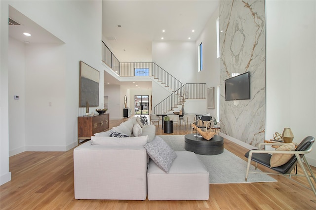 living room with a towering ceiling and light wood-type flooring