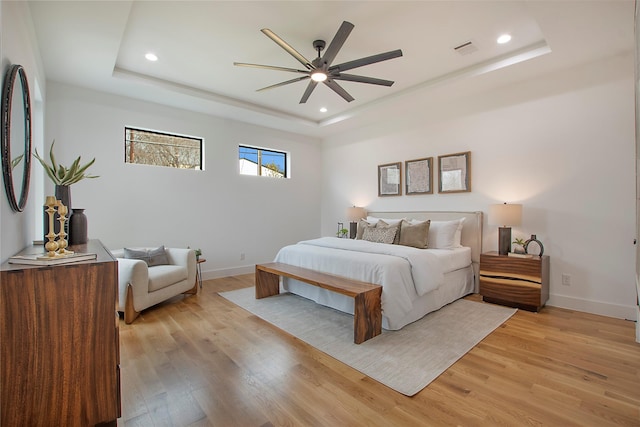 bedroom featuring a raised ceiling, ceiling fan, and light hardwood / wood-style floors