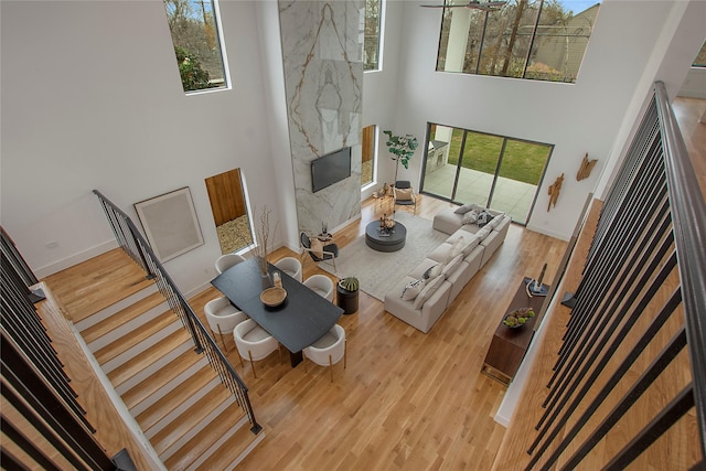 living room with a fireplace, a towering ceiling, light hardwood / wood-style floors, and a wealth of natural light