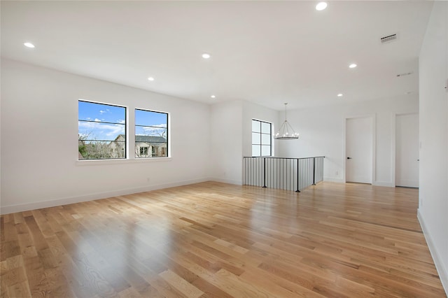 empty room featuring an inviting chandelier and light hardwood / wood-style flooring