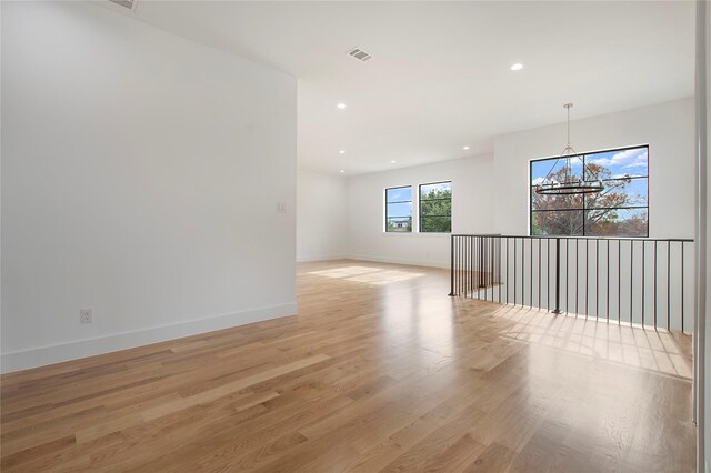 unfurnished room featuring light hardwood / wood-style flooring and a notable chandelier