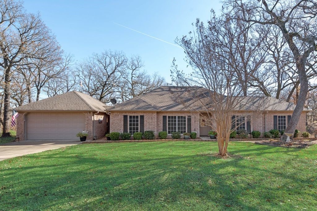 ranch-style home with a garage and a front lawn