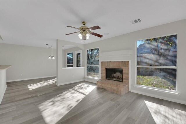 unfurnished living room featuring ceiling fan, hardwood / wood-style floors, and a brick fireplace