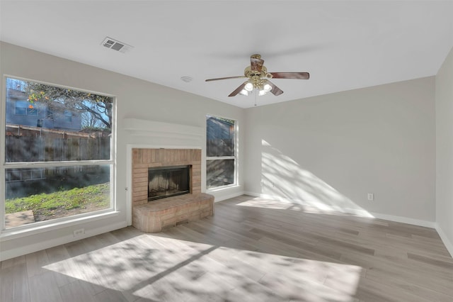 unfurnished living room with a brick fireplace, ceiling fan, and light hardwood / wood-style flooring