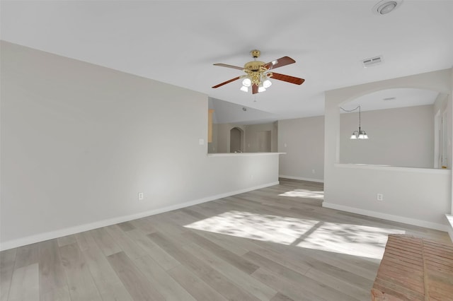 unfurnished living room with ceiling fan with notable chandelier and light hardwood / wood-style flooring