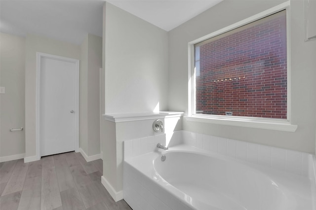 bathroom with wood-type flooring and tiled tub